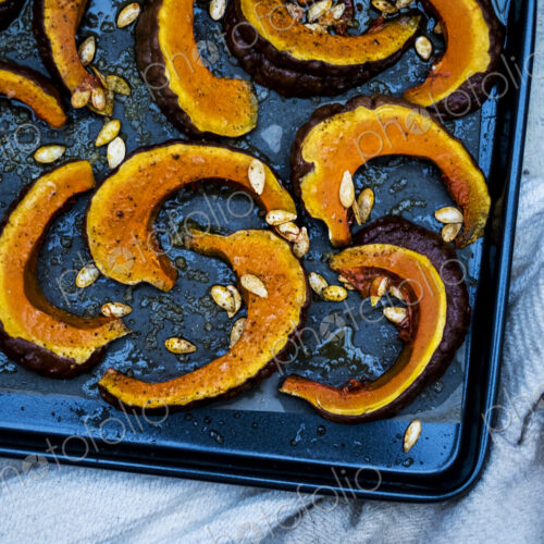High angle close up of slices of pumpkin on a baking tray. High angle close up of slices of pumpkin on a baking tray.