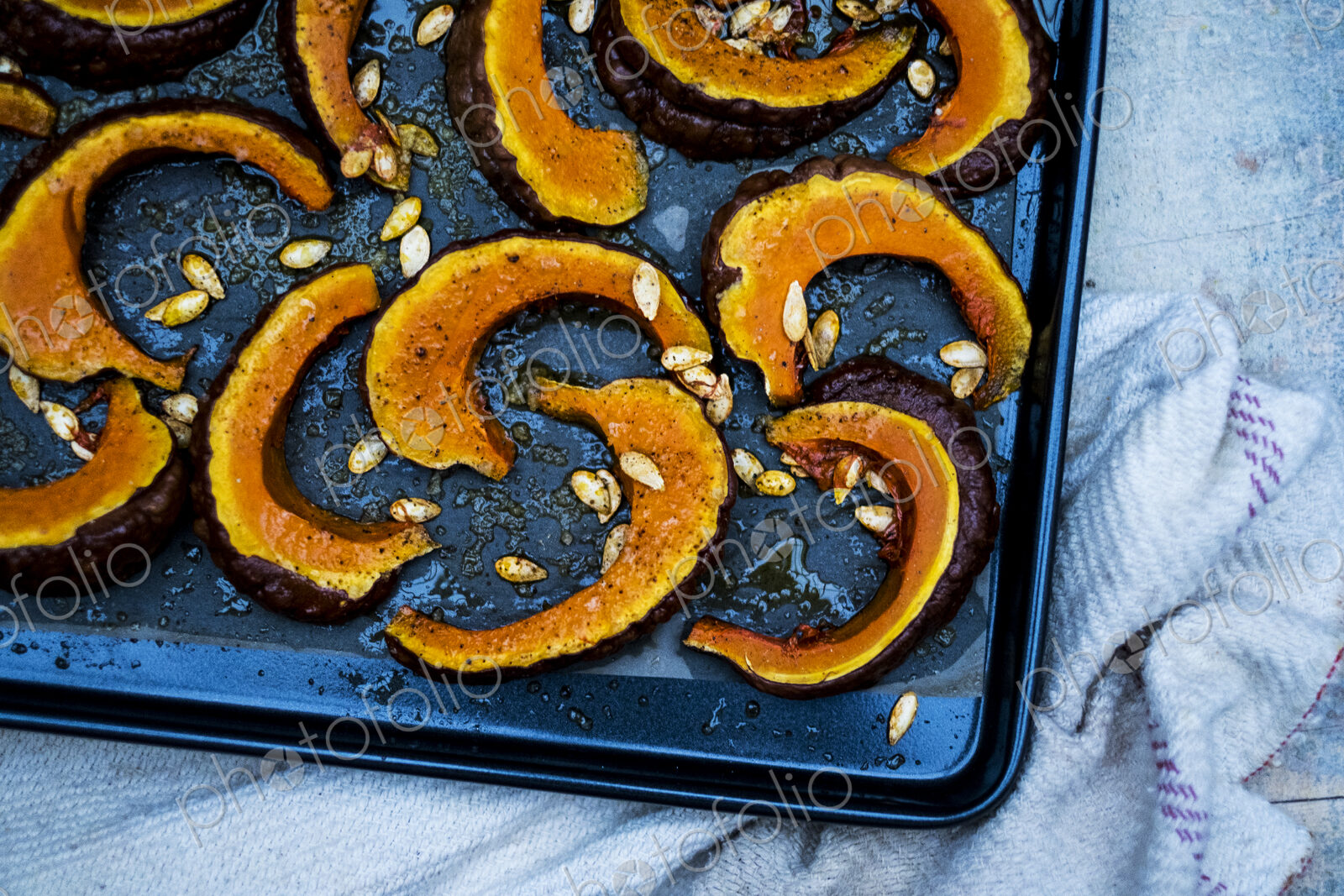 High angle close up of slices of pumpkin on a baking tray.