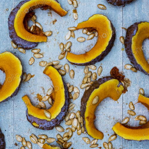 High angle close up of slices of pumpkin on blue background. High angle close up of slices of pumpkin on blue background.
