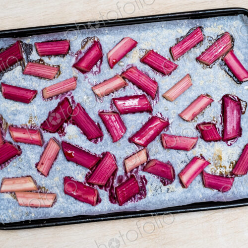 High angle close up of slices of rhubarb on a baking tray. High angle close up of slices of rhubarb on a baking tray.