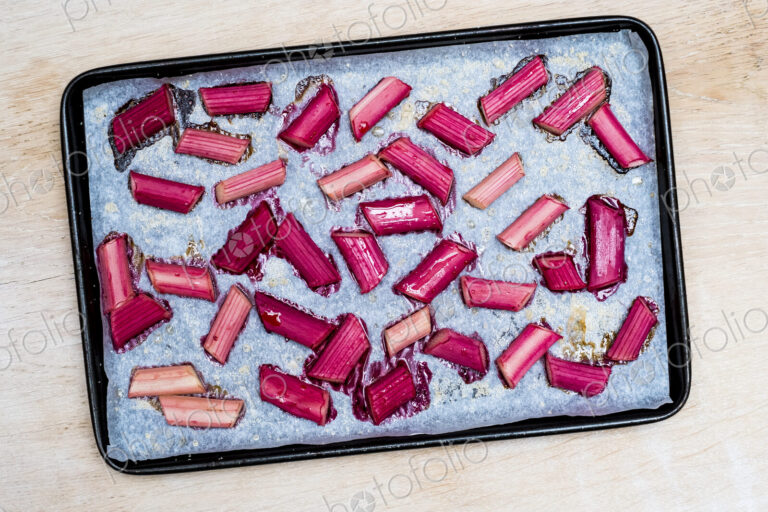 High angle close up of slices of rhubarb on a baking tray.