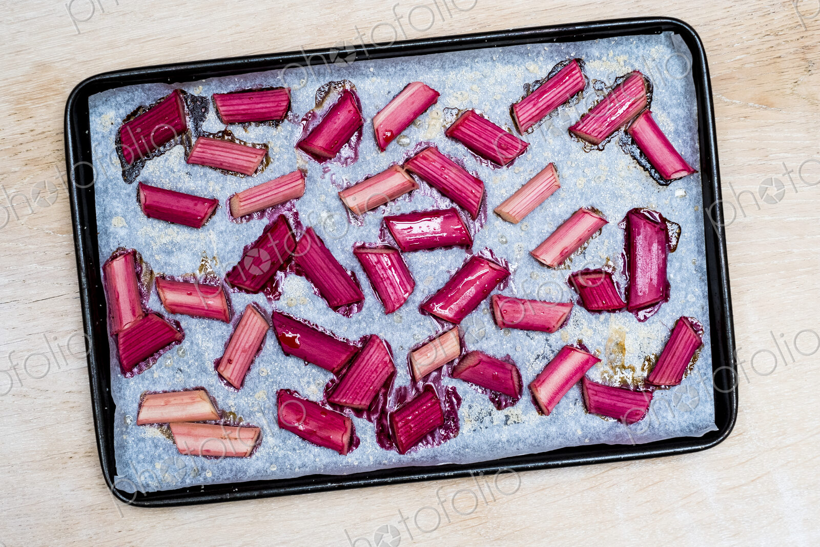 High angle close up of slices of rhubarb on a baking tray.
