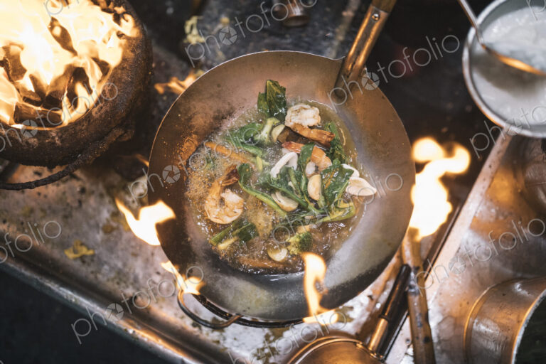 High angle close up of stir fry with prawns and green vegetables in stainless steel…