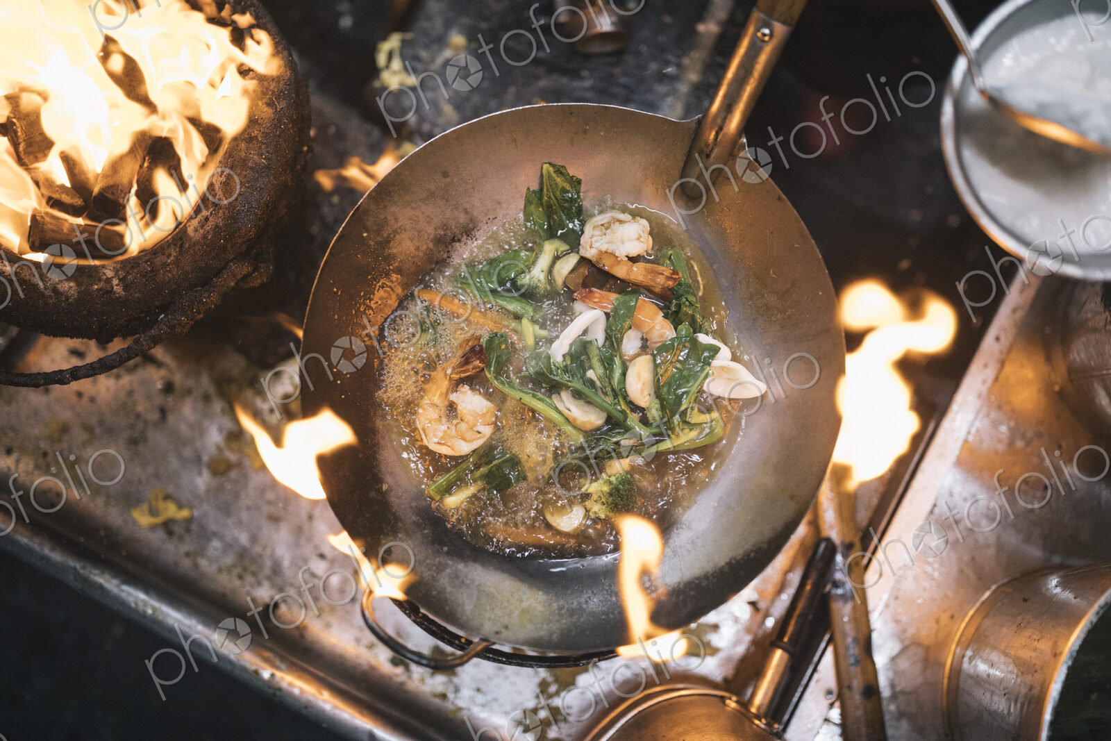 High angle close up of stir fry with prawns and green vegetables in stainless steel…