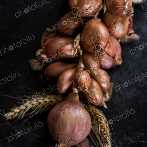 High angle close up of string of onions and garlic on black background. High angle close up of string of onions and garlic on black background.