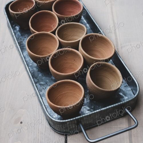 High angle close up of terracotta plant pots on metal tray.