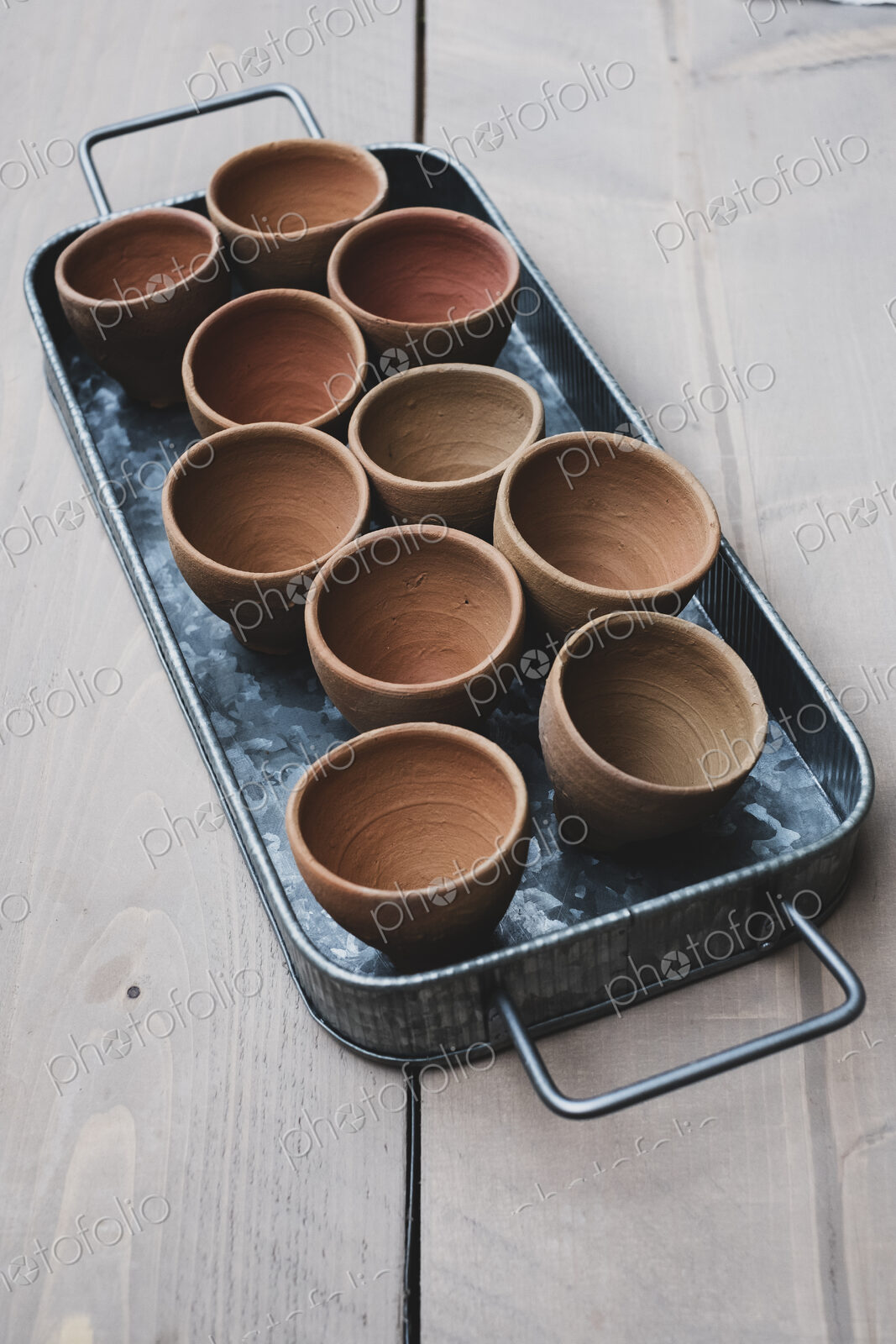 High angle close up of terracotta plant pots on metal tray.