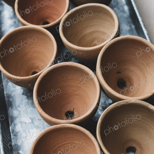 High angle close up of terracotta plant pots on metal tray.