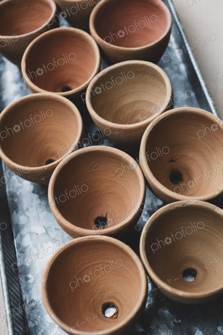 High angle close up of terracotta plant pots on metal tray.