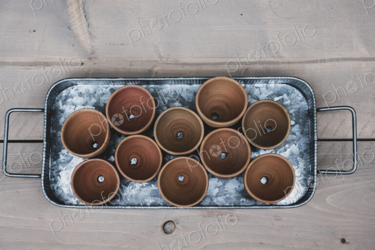 High angle close up of terracotta plant pots on metal tray.