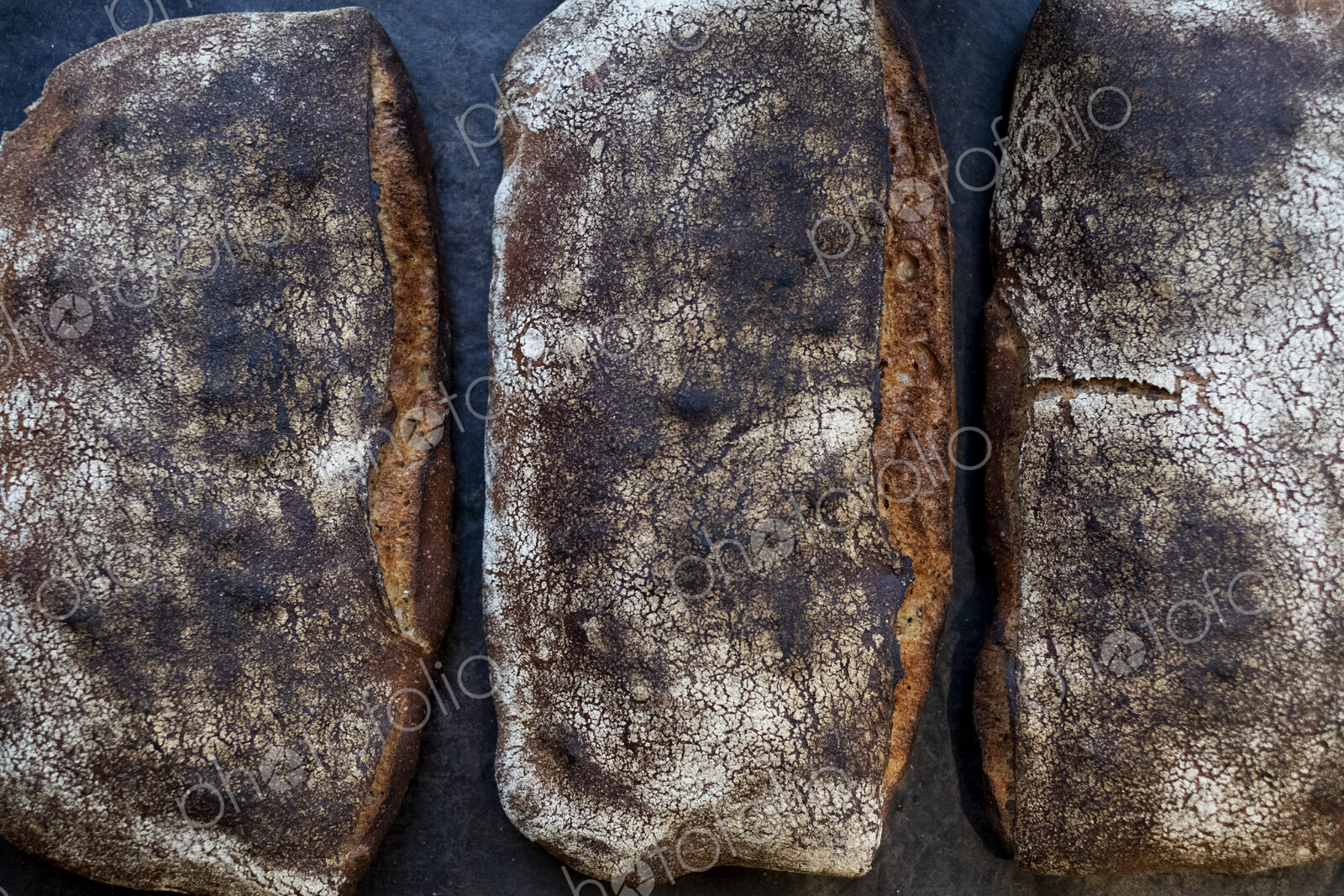 High angle close up of three freshly baked loaves of bread in an artisan bakery.