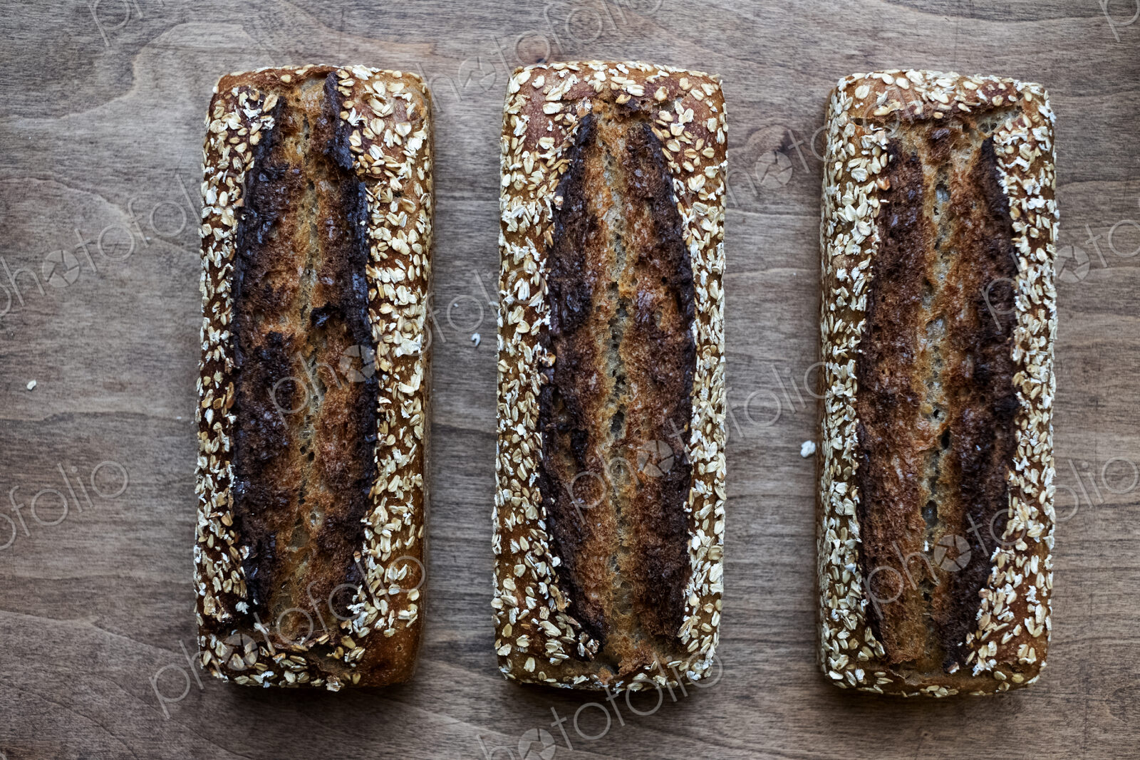 High angle close up of three freshly baked seeded loaves of bread in an artisan bakery.