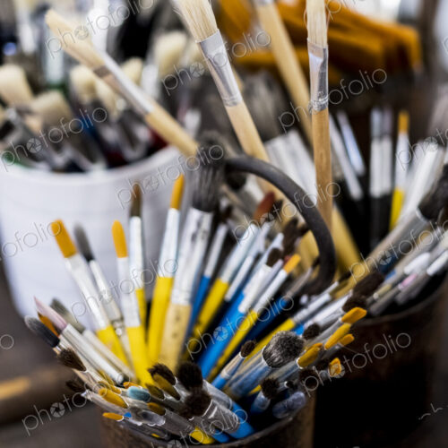 High angle close up of tins with selection of paintbrushes in various sizes.