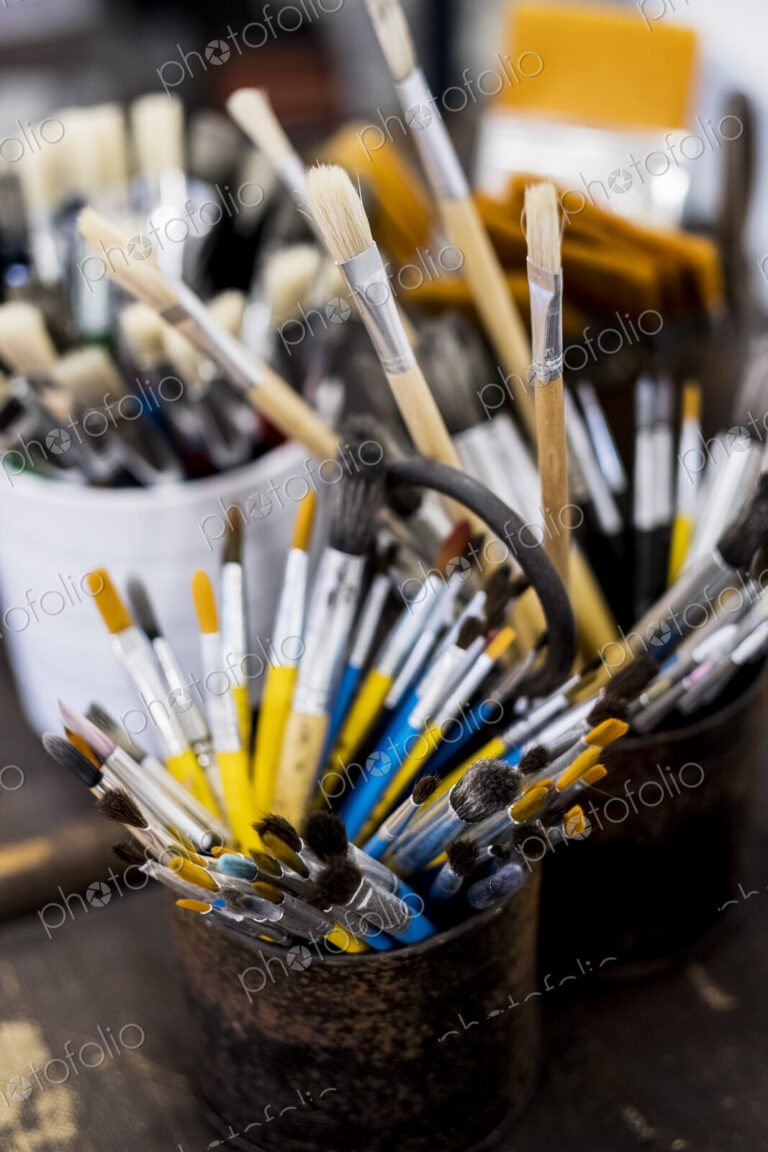 High angle close up of tins with selection of paintbrushes in various sizes.
