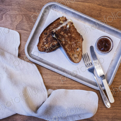 High angle close up of toasted slice of bread, jam and cutlery on tray in an artisan…