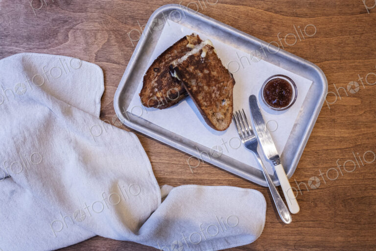 High angle close up of toasted slice of bread, jam and cutlery on tray in an artisan…