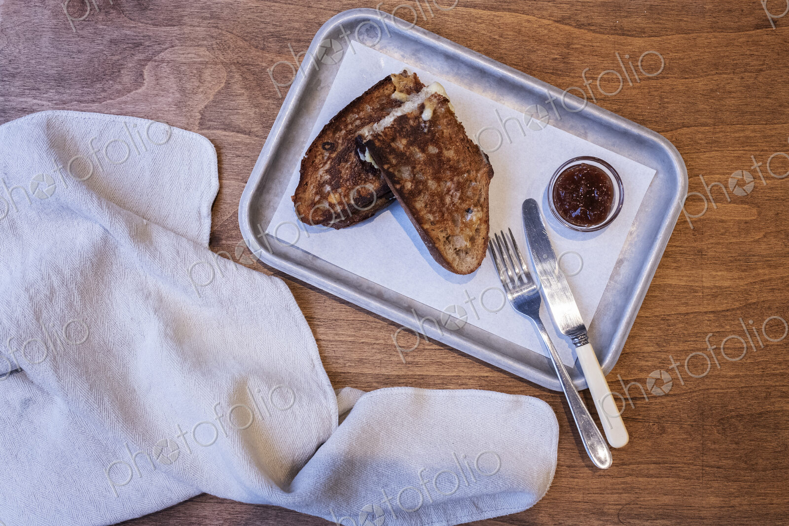 High angle close up of toasted slice of bread, jam and cutlery on tray in an artisan…