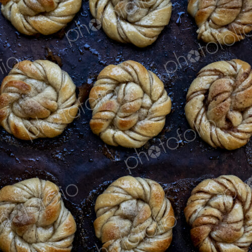 High angle close up of tray with freshly baked cinnamon buns in an artisan bakery.