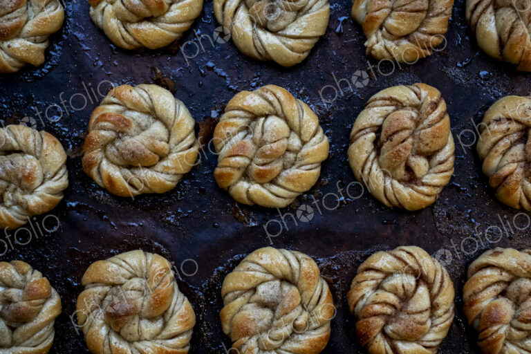 High angle close up of tray with freshly baked cinnamon buns in an artisan bakery.
