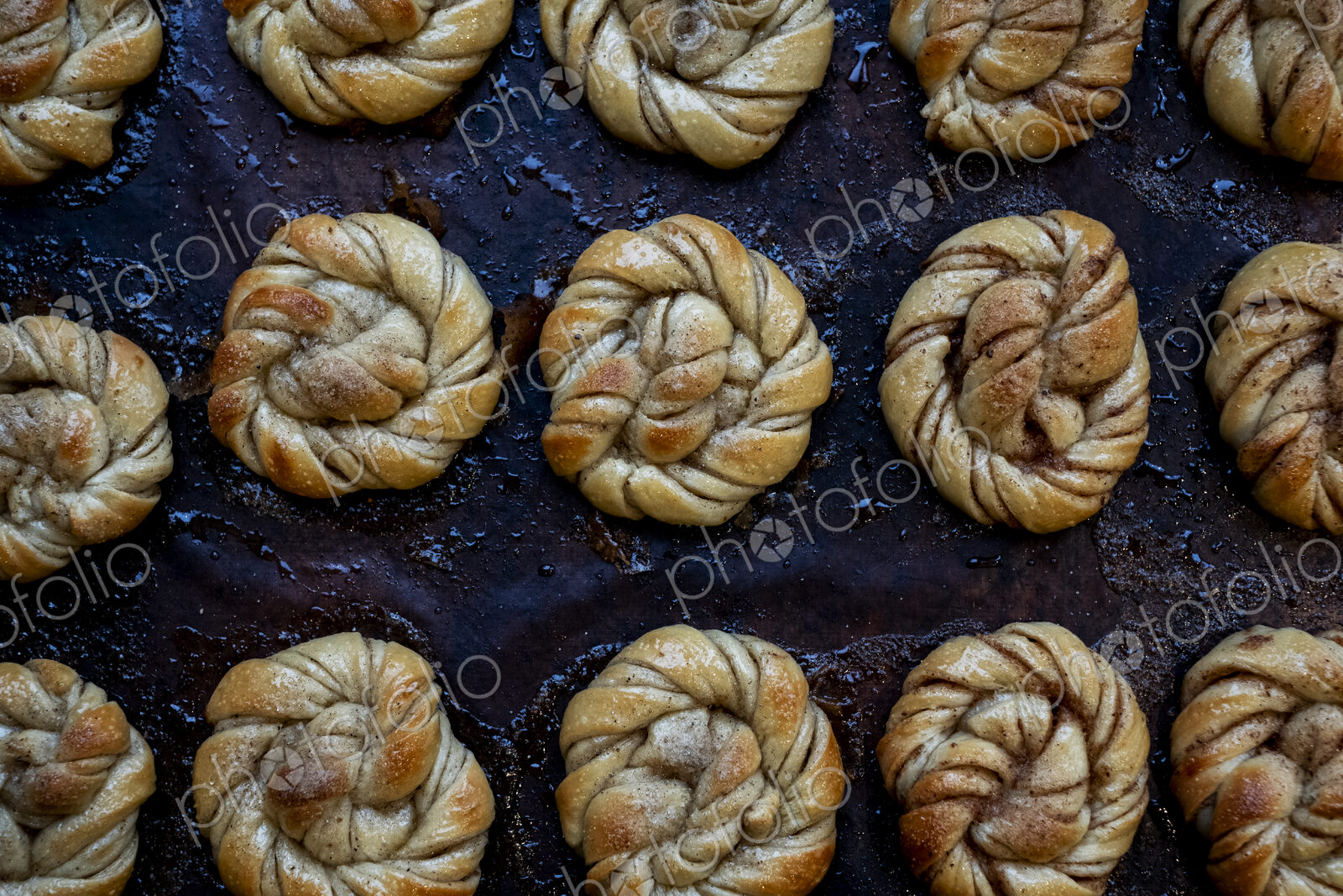 High angle close up of tray with freshly baked cinnamon buns in an artisan bakery.