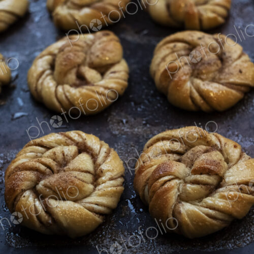 High angle close up of tray with freshly baked cinnamon buns in an artisan bakery.