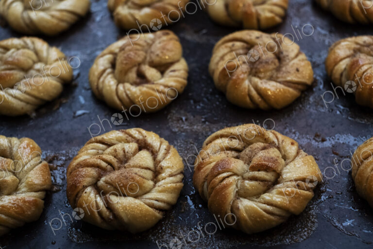 High angle close up of tray with freshly baked cinnamon buns in an artisan bakery.