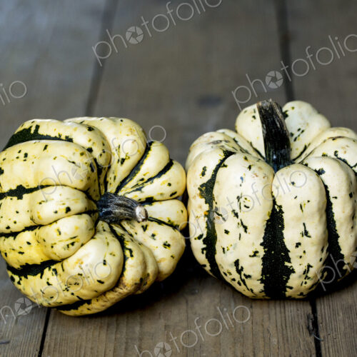 High angle close up of two Sweet Dumpling squash on rustic wooden table.