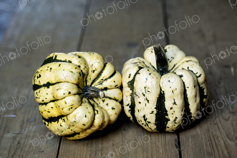 High angle close up of two Sweet Dumpling squash on rustic wooden table.