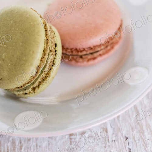High angle close up of two macaroons on a white plate.