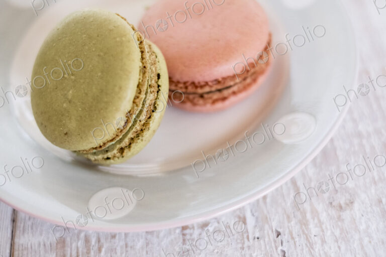 High angle close up of two macaroons on a white plate.