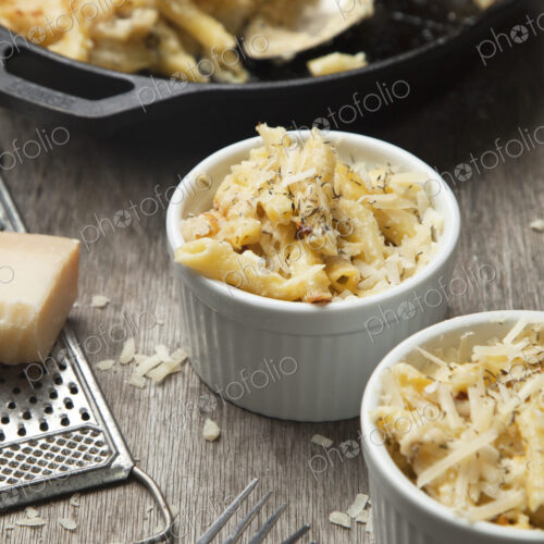 High angle close up of two ramekins and a dish with mac and cheese, cheese sauce and… High angle close up of two ramekins and a dish with mac and cheese, cheese sauce and…