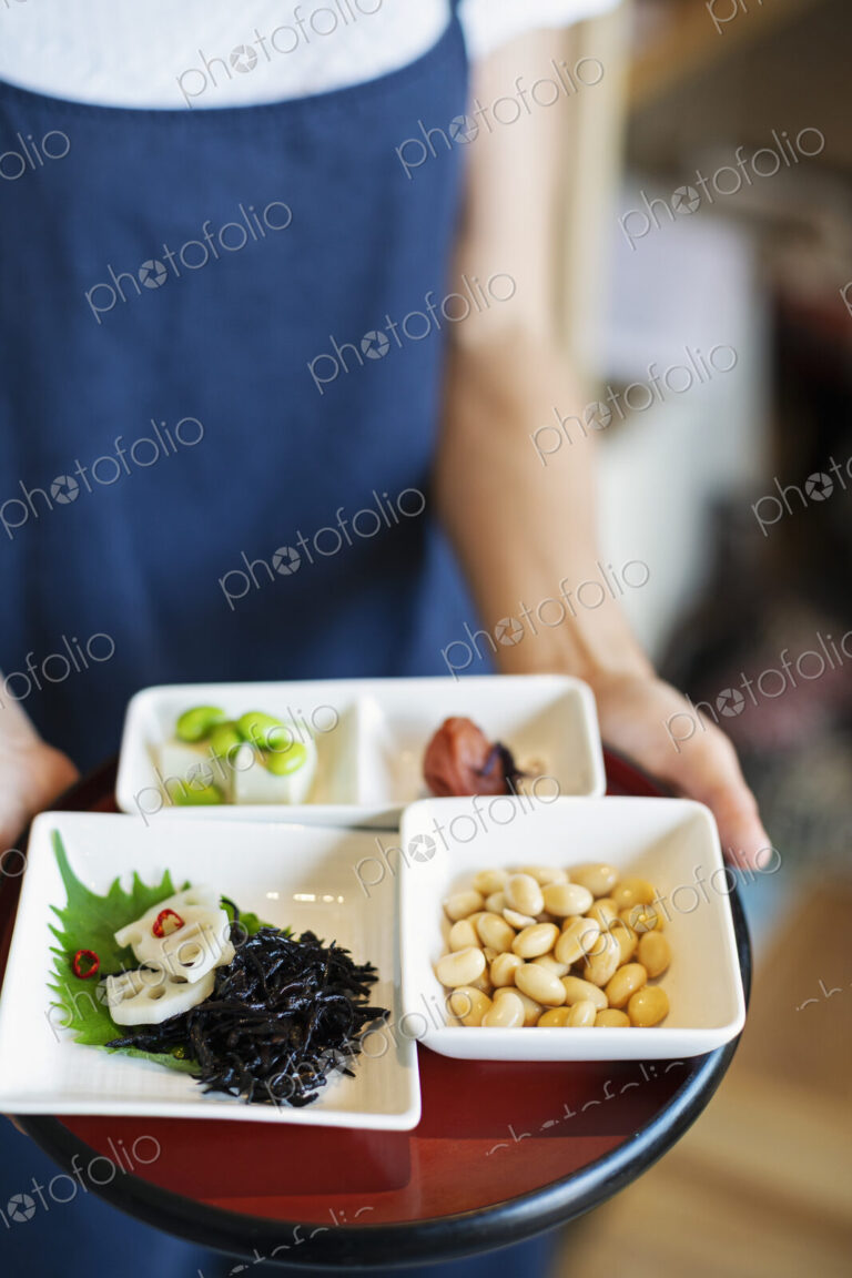 High angle close up of waitress holding a selection of vegetarian Japanese foods in a…