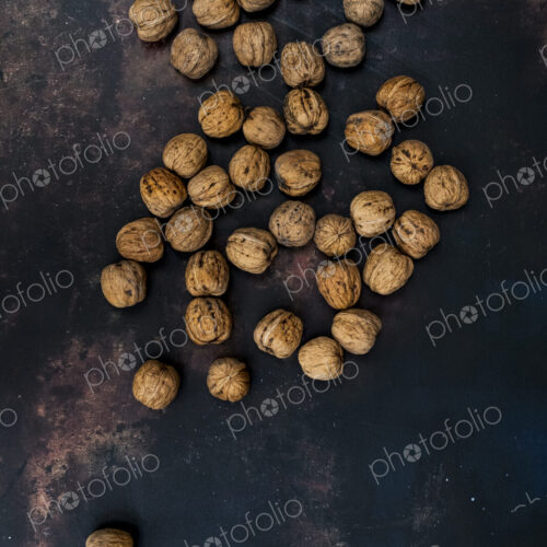 High angle close up of walnuts on black rusty surface. High angle close up of walnuts on black rusty surface.
