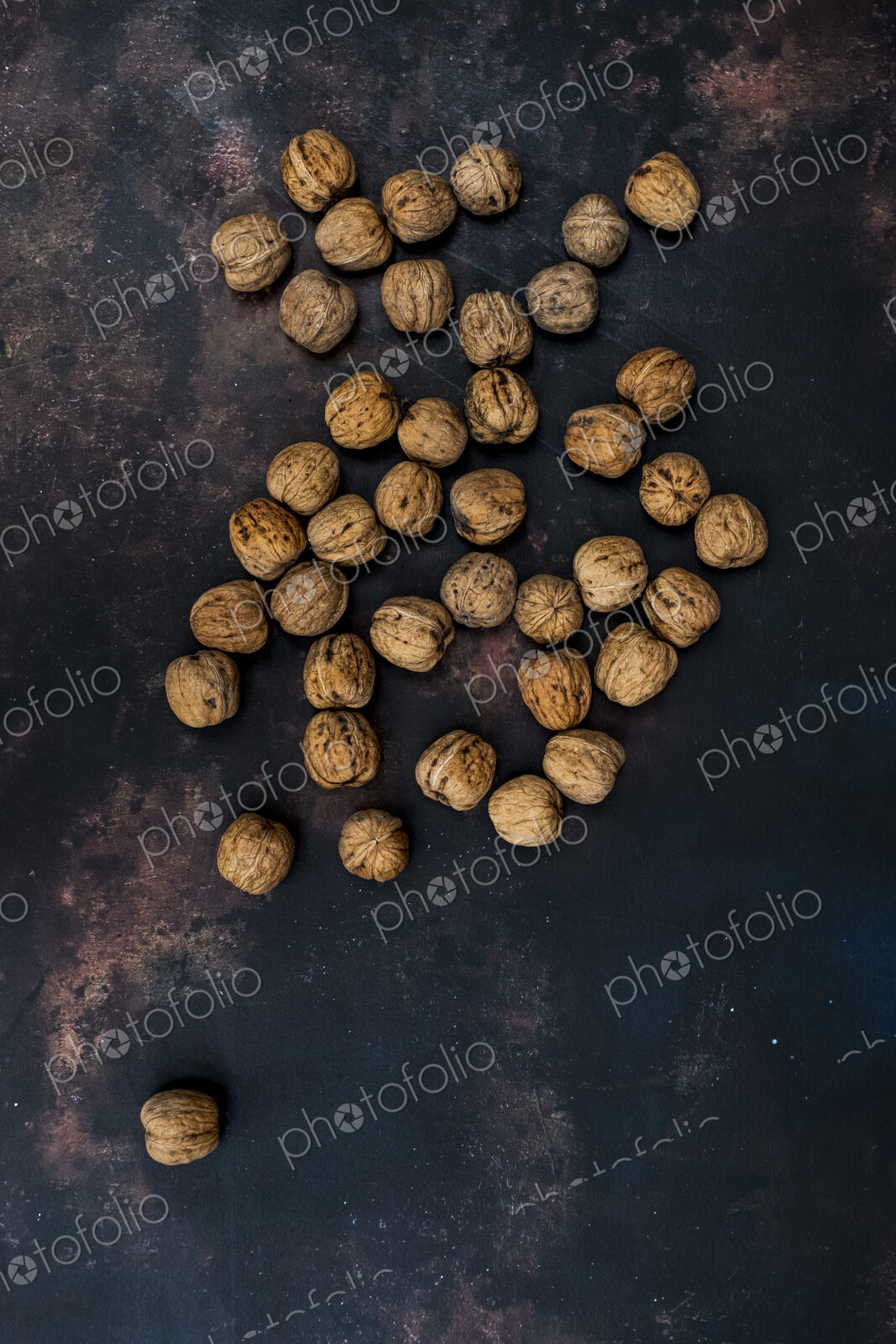 High angle close up of walnuts on black rusty surface.