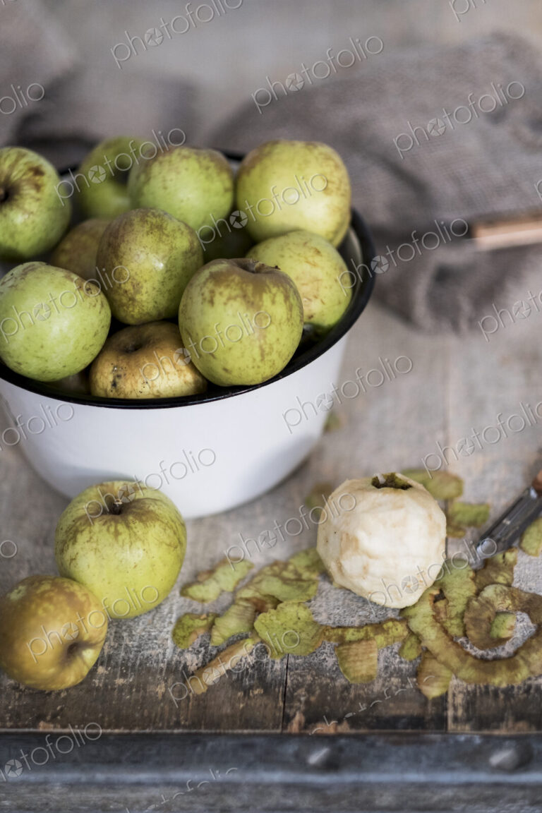 High angle close up of white bowl with green apples.