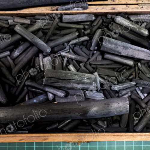 High angle close up of wooden box with a selection of artist's charcoal sticks in…