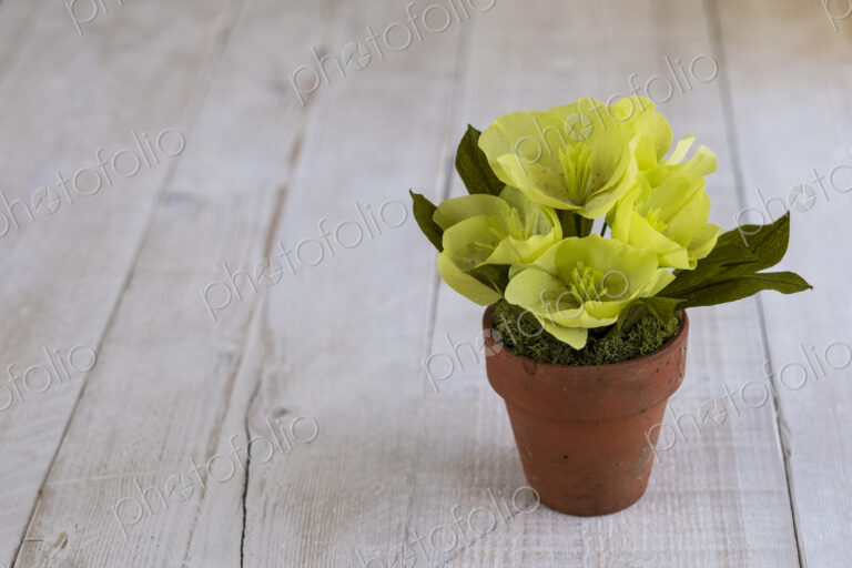 High angle close up of yellow paper flowers in a terracotta flowerpot.