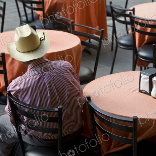 High angle rear view of man wearing Stetson hat sitting a ta a table in a restaurant. High angle rear view of man wearing Stetson hat sitting a ta a table in a restaurant.