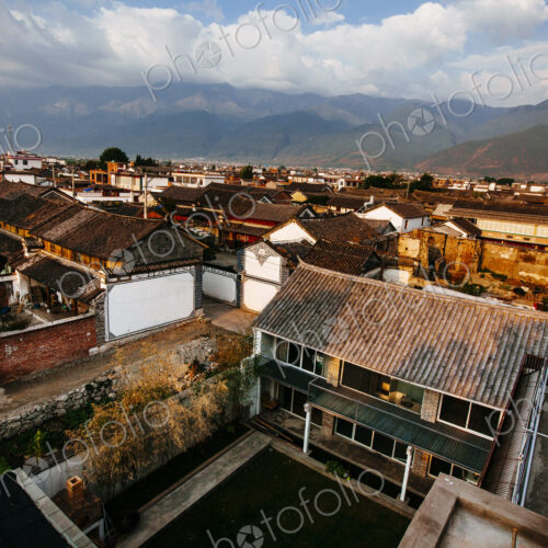 High angle view across rooftops of traditional Asian houses, mountains in the distance. High angle view across rooftops of traditional Asian houses, mountains in the distance.