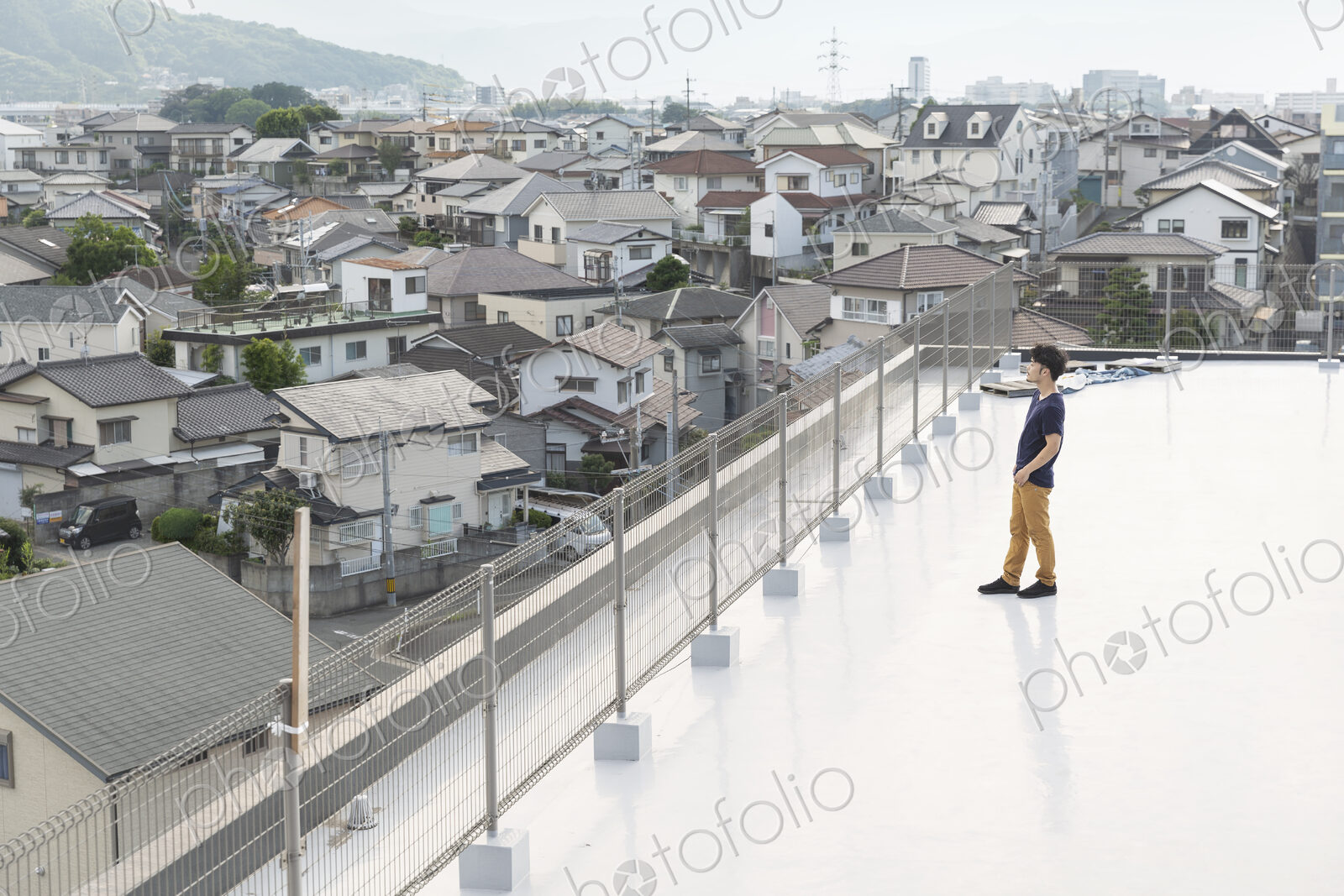 High angle view of Japanese man standing on a rooftop in an urban setting.
