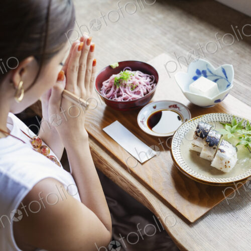High angle view of Japanese woman sitting at a table in a Japanese restaurant, eating. High angle view of Japanese woman sitting at a table in a Japanese restaurant, eating.