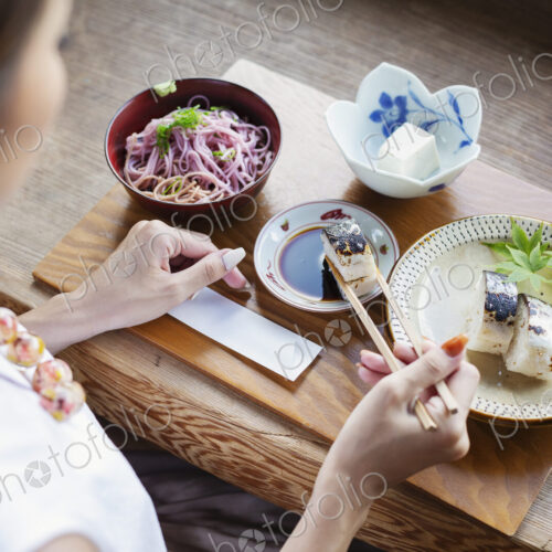 High angle view of Japanese woman sitting at a table in a Japanese restaurant, eating. High angle view of Japanese woman sitting at a table in a Japanese restaurant, eating.