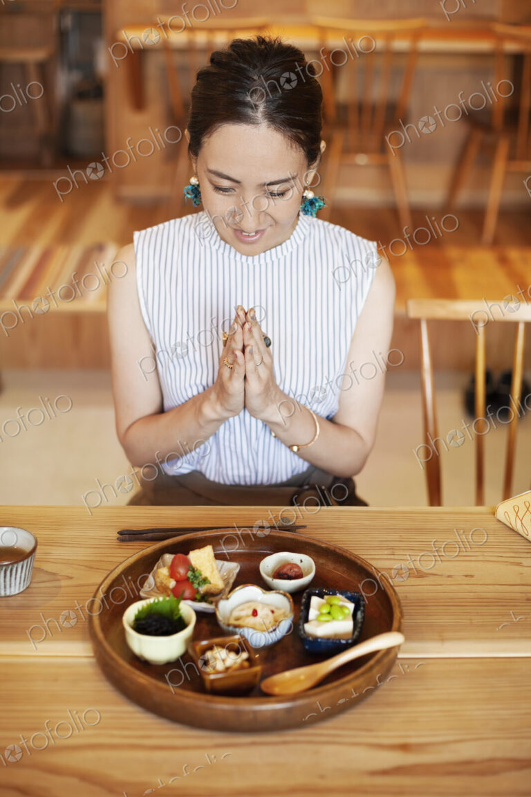 High angle view of Japanese woman sitting in front of a selection of vegetarian food…