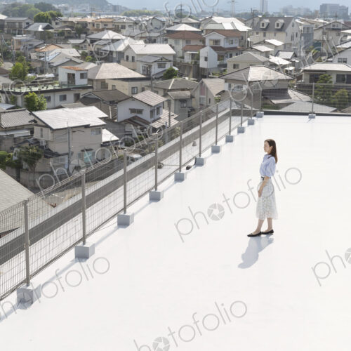 High angle view of Japanese woman standing on a rooftop in an urban setting.