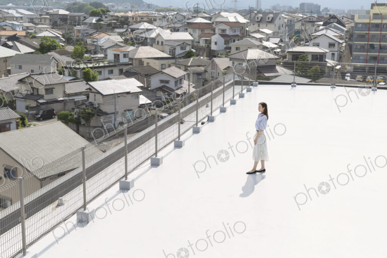 High angle view of Japanese woman standing on a rooftop in an urban setting.