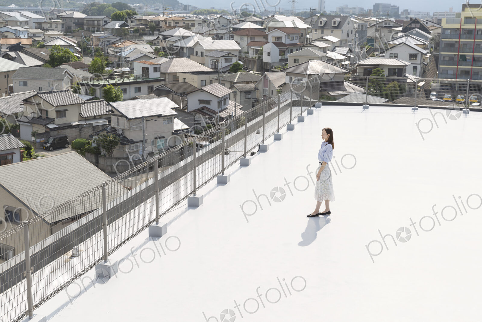 High angle view of Japanese woman standing on a rooftop in an urban setting.