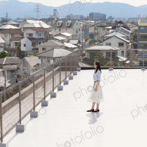 High angle view of Japanese woman standing on a rooftop in an urban setting. High angle view of Japanese woman standing on a rooftop in an urban setting.