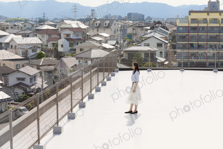 High angle view of Japanese woman standing on a rooftop in an urban setting.
