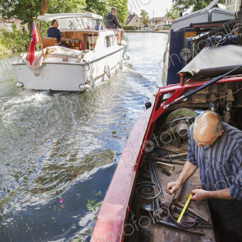 High angle view of a blacksmith working at his bench on a narrowboat on the water,… High angle view of a blacksmith working at his bench on a narrowboat on the water,…
