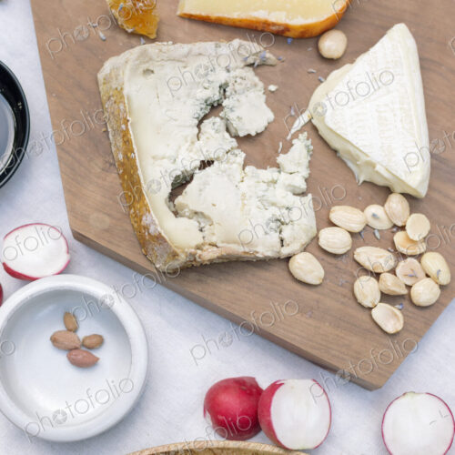 High angle view of a cheese board, cheese, olives, nuts and radishes on a table.